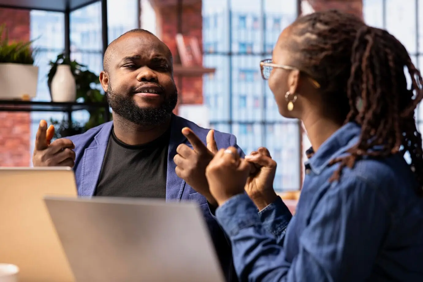 Радостные удалённые сотрудники за столом празднуют завершение задачи на ноутбуке.